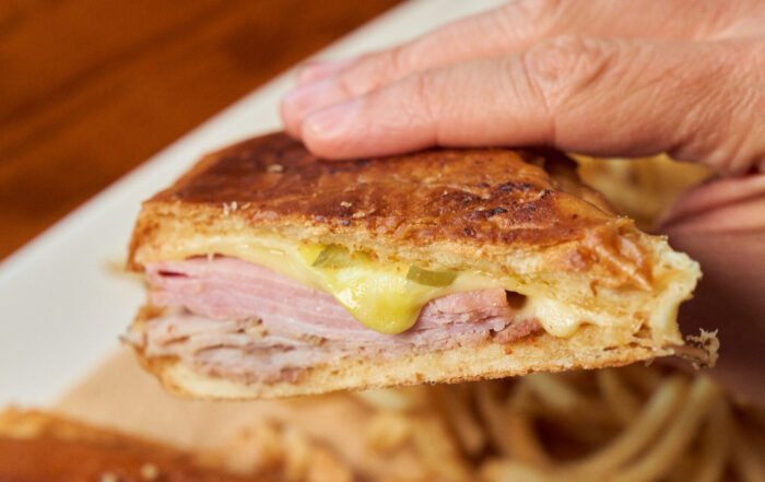 Hand holding half of a Cuban Sandwich