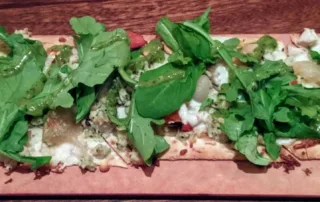 Flat bread with arugala on a board