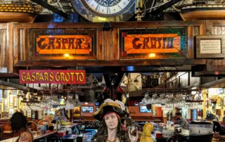 The entrance to Gaspars Grotto inlucing a clock, female statue of a pirate and the name Gaspars Grotto in stained glass
