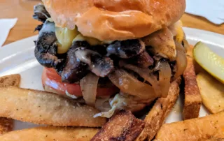 a huge mushroom swiss burger and steak fries