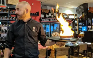 Server with blazing dish of chorizo
