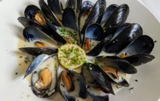 Mussels in a white cream sauce with a lemon garnish