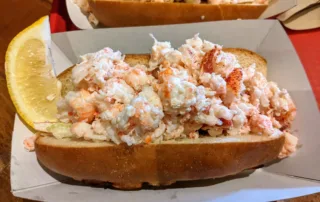 a lobster roll with a lemon wedge