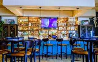 Stools and hightop tables in front of a stocked bar