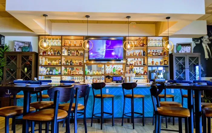 Stools and hightop tables in front of a stocked bar