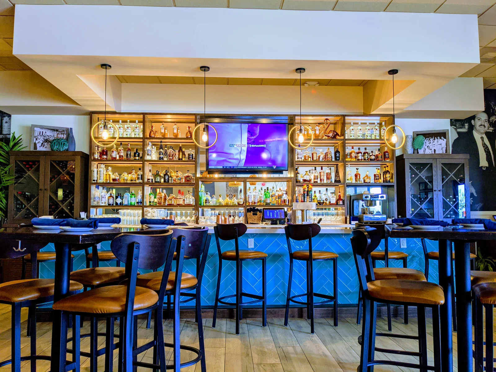 Stools and hightop tables in front of a stocked bar