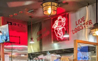 Neon Lobster sign hanging over kitchen in Kelly's