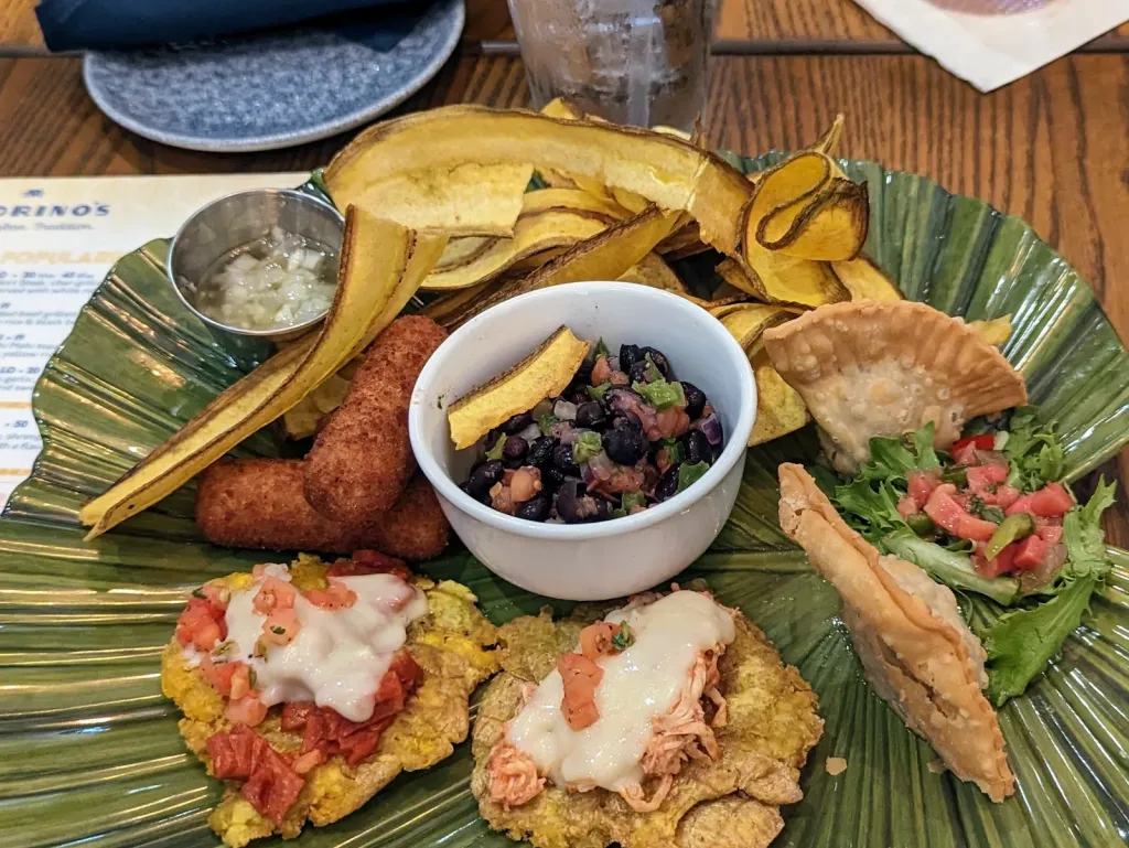 The Cuban combination platter for consisting of Fiesta tostones, croquetas de jamon, picadillo empanadas, mariquitas, and black bean salsa.