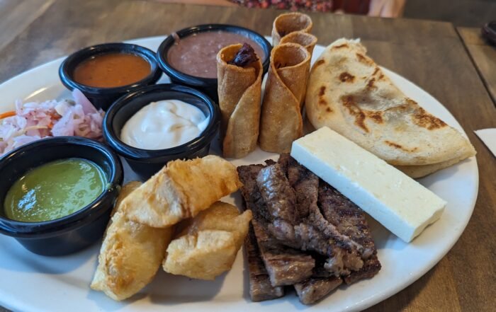 Chicken Tamale, Sweet Corn Tamale, Papusa, Fried Yucca, Salvadorian Cream, white cheese, pickled cabbage, red sauce, and spicy salsa verde.