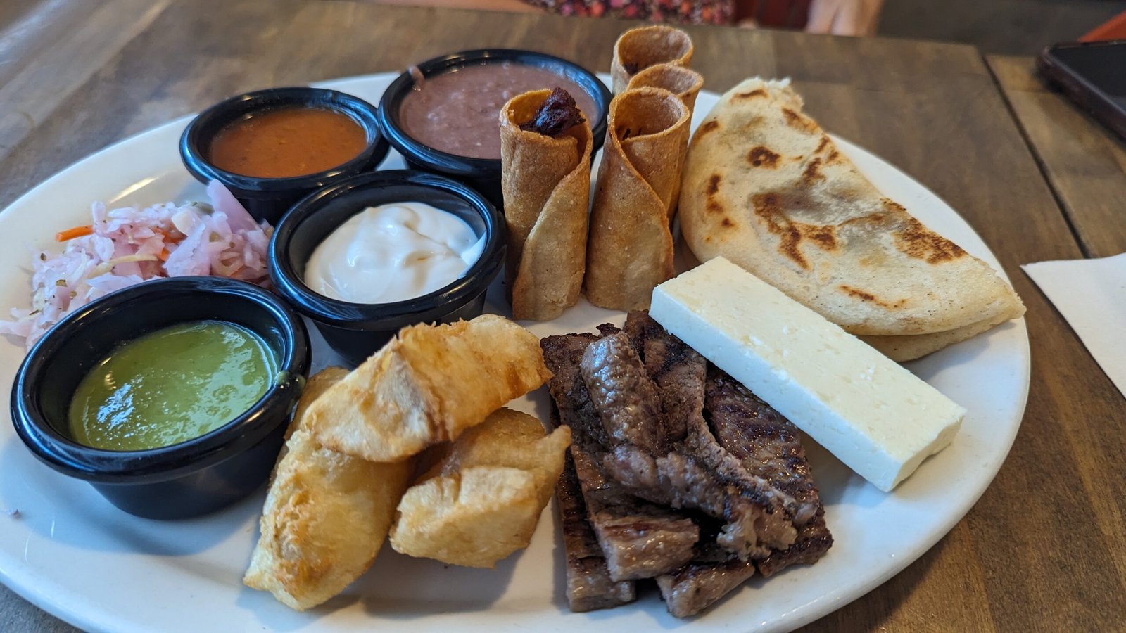 Chicken Tamale, Sweet Corn Tamale, Papusa, Fried Yucca, Salvadorian Cream, white cheese, pickled cabbage, red sauce, and spicy salsa verde.