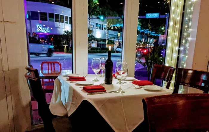 A set table with a bottle of wine in the window of Cafe Ragazzi