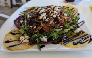 A yellow and red beet salad topped with balsamic glaze and cheese crumbles