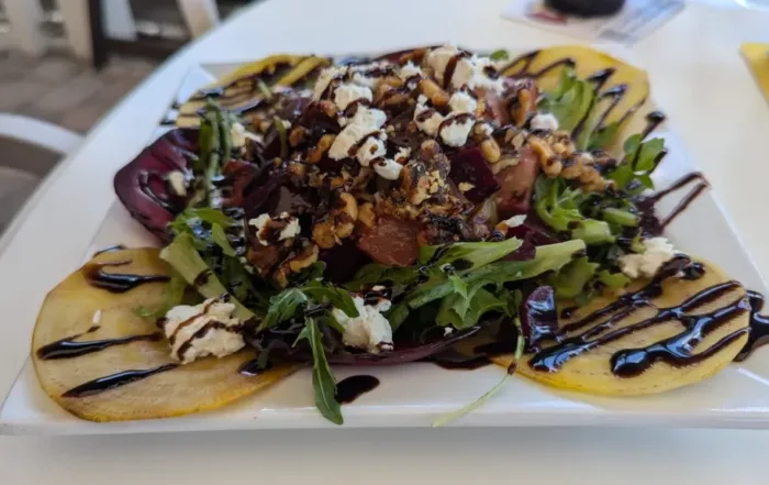A yellow and red beet salad topped with balsamic glaze and cheese crumbles