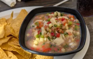 A bowl oc Cervichi (mixed seafood in an citic brine) and plantain chips