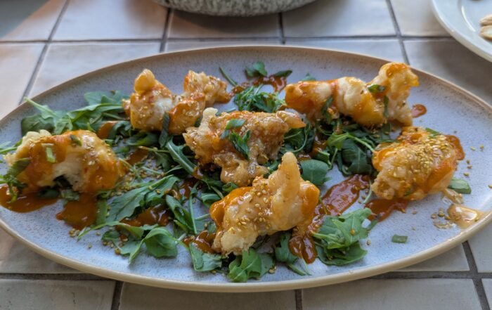Crispy Shrimp Tossed in garlic–sweet chili, served with frisée & toasted sesame seeds