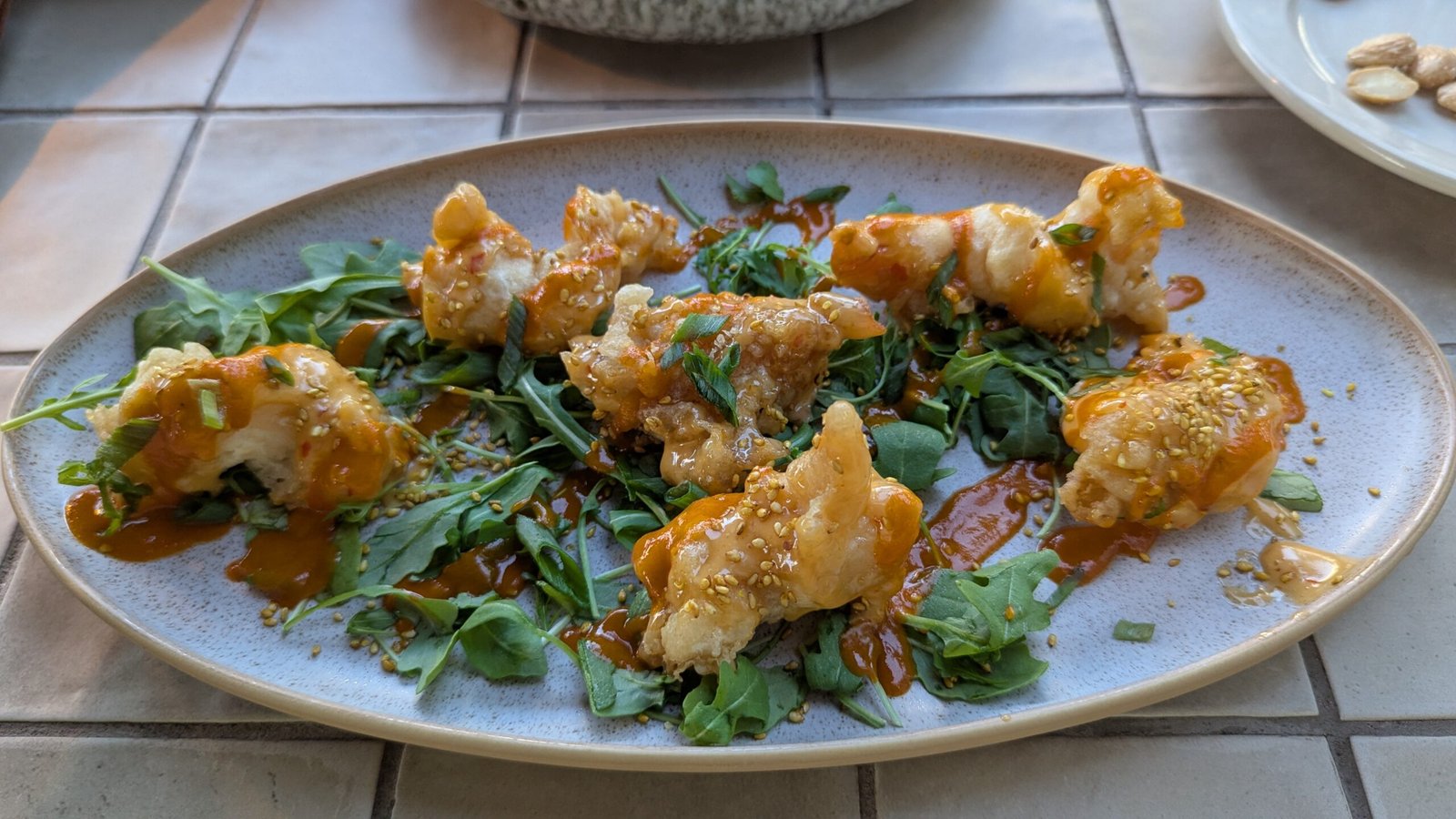 Crispy Shrimp Tossed in garlic–sweet chili, served with frisée & toasted sesame seeds