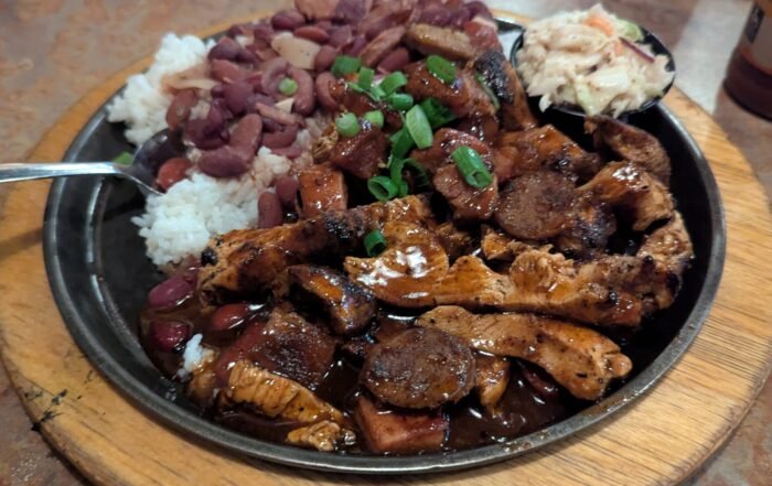 A Plate of assorted Grilled meats and a side of red beans and rice.