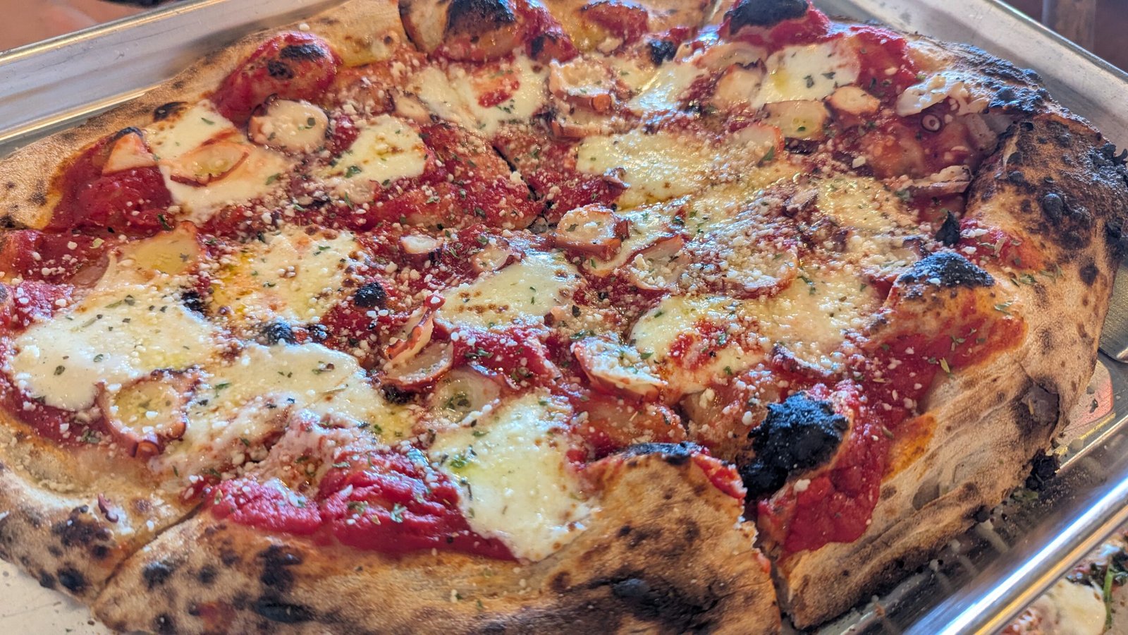 Sardegna: Pizza topped with thinly sliced, perfectly grilled octopus, fresh mozzarella, garlic, and parsley. Finished with Pecorino Romano and a drizzle of EVOO